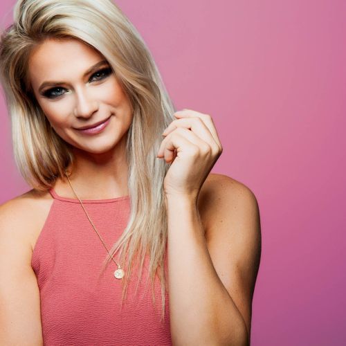 Vrouw met blonde haren en roze achtergrond.